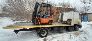 Эвакуатор перевозит погрузчик